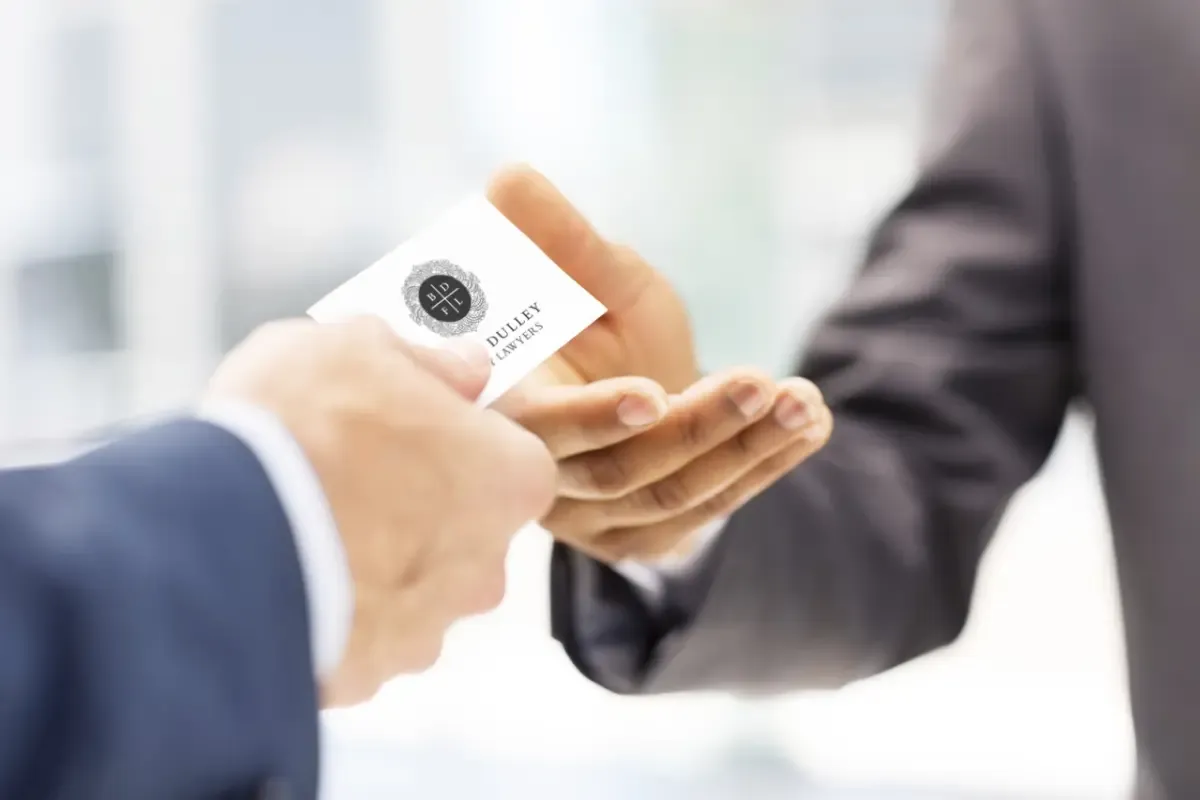 A client being handed a Bruce Dulley Family Lawyers business card